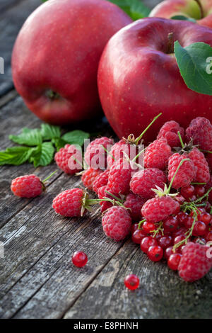 Ribes rosso, rasberry e mele rosse sul vecchio tavolo in legno, mix di colore rosso vitamine concept Foto Stock