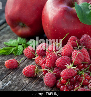 Ribes rosso, rasberry e mele rosse sul vecchio tavolo in legno, mix di colore rosso vitamine concept Foto Stock