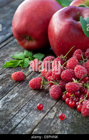Ribes rosso, rasberry e mele rosse sul vecchio tavolo in legno, mix di colore rosso vitamine concept