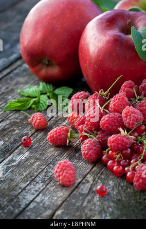 Ribes rosso, rasberry e mele rosse sul vecchio tavolo in legno, mix di colore rosso vitamine concept Foto Stock