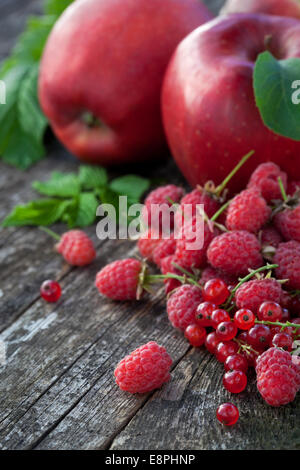 Ribes rosso, rasberry e mele rosse sul vecchio tavolo in legno, mix di colore rosso vitamine concept Foto Stock