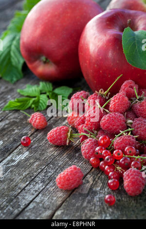 Ribes rosso, rasberry e mele rosse sul vecchio tavolo in legno, mix di colore rosso vitamine concept Foto Stock