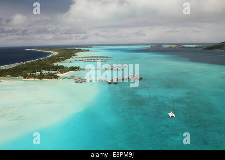 Vista aerea di motu e laguna con acqua oltre bungalows Foto Stock