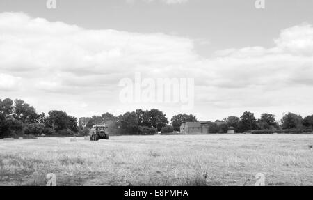 Il trattore imballano paglia trinciata in una fattoria inglese field - elaborazione monocromatica Foto Stock