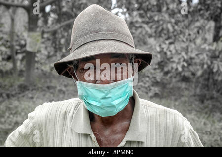 Il nord di Sumatra, Indonesia. Xiii oct, 2014. Un uomo che indossa la maschera per evitare l'inalazione di cenere dall'eruzione del Monte Sinabung a Sibintun villaggio nel nord di Sumatra, Indonesia, 13 ottobre, 2014. Il vulcano Mount Sinabung è tra più di 120 vulcani attivi in Indonesia e aveva eruttato per quattro volte dal precedente domenica. Credito: Tanto H./Xinhua/Alamy Live News Foto Stock