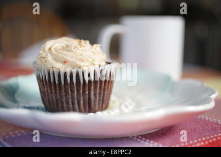 Il cioccolato burro di arachidi cupcake su una piastra con una tazza di caffè su un tavolo Foto Stock