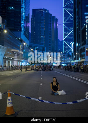 Hong Kong. Xiii oct, 2014. Hong Kong le proteste: studenti, pro militanti per la democrazia e gli altri sostenitori di occupare centrale, ora chiamato il movimento ombrello o l'ombrello rivoluzione, sono camping lungo Queensway in Admiralty. Barricate e tende sono state erette dai manifestanti dopo un tentativo di smantellare in precedenza durante la giornata. Un manifestante solitario siede su Queensway. Foto Stock