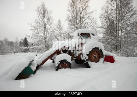 Un vintage David Brown trattore con caricatore e la pala per la rimozione di neve è coperto con neve alta. Foto Stock