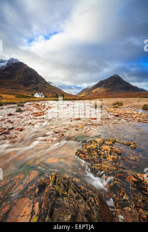 Il fiume Coupall in Glen Coe, Scozia con Lagangarbh Cottage in distanza. Foto Stock