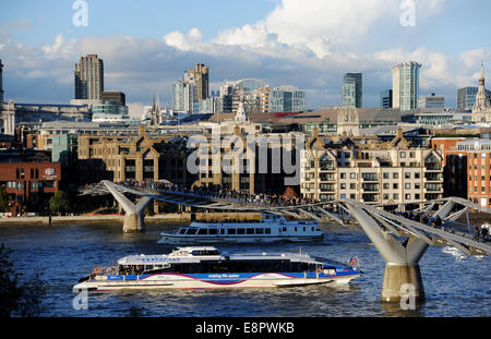 Londra Regno Unito - Vista attraverso il Tamigi verso gli uffici e le gru della città di Londra con il ponte pedonale Millennium Foto Stock