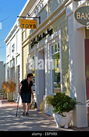 Donna disabile con canna cammina giù Novato street per lo shopping Foto Stock