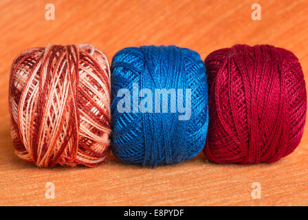 Tre sfere di un multi-filato colorato su uno sfondo arancione Foto Stock