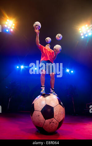 Zhora Oganisyan, il calcio giocoliere dal Moscow State Circus, i tentativi di equilibrio su un gigante di calcio mentre la giocoleria 3 palloni da calcio con la sua mano contemporaneamente e il tentativo di "mantenere l' un supplemento di calcio da sfogliare dal piede al piede ad Alexandra Palace offre: Zhora Oganisyan dove: Londra, Regno Unito quando: 10 Apr 2014 Foto Stock