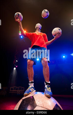 Zhora Oganisyan, il calcio giocoliere dal Moscow State Circus, i tentativi di equilibrio su un gigante di calcio mentre la giocoleria 3 palloni da calcio con la sua mano contemporaneamente e il tentativo di "mantenere l' un supplemento di calcio da sfogliare dal piede al piede ad Alexandra Palace offre: Zhora Oganisyan dove: Londra, Regno Unito quando: 10 Apr 2014 Foto Stock