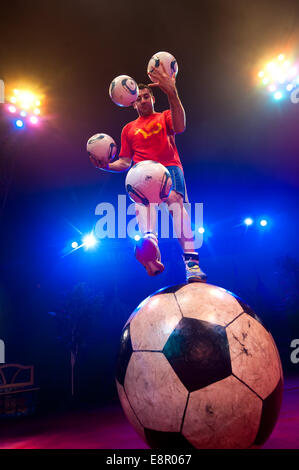 Zhora Oganisyan, il calcio giocoliere dal Moscow State Circus, i tentativi di equilibrio su un gigante di calcio mentre la giocoleria 3 palloni da calcio con la sua mano contemporaneamente e il tentativo di "mantenere l' un supplemento di calcio da sfogliare dal piede al piede ad Alexandra Palace offre: Zhora Oganisyan dove: Londra, Regno Unito quando: 10 Apr 2014 Foto Stock