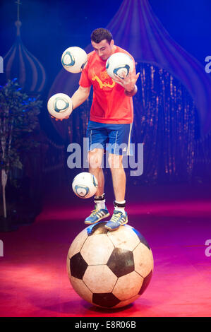 Zhora Oganisyan, il calcio giocoliere dal Moscow State Circus, i tentativi di equilibrio su un gigante di calcio mentre la giocoleria 3 palloni da calcio con la sua mano contemporaneamente e il tentativo di "mantenere l' un supplemento di calcio da sfogliare dal piede al piede ad Alexandra Palace offre: Zhora Oganisyan dove: Londra, Regno Unito quando: 10 Apr 2014 Foto Stock