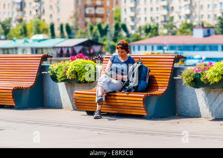 Mosca, Russia. 22 Luglio 2014: una donna non identificato si siede su una panchina del terrapieno di Puskin di Mosca Gorky Park Foto Stock