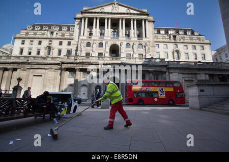 Il pulitore di strada spazza i rifiuti di fronte alla Bank of England su Threadneedle Street nella City di Londra, Regno Unito. Foto Stock
