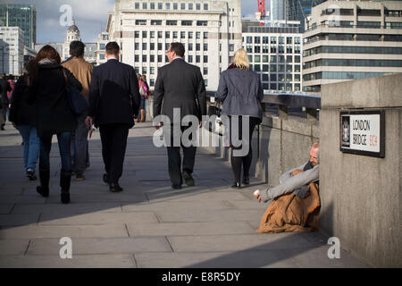 I ricchi poveri dividono le disuguaglianze, i senzatetto si accaniscono sul London Bridge chiedendo soldi ai lavoratori cittadini di Londra Foto Stock