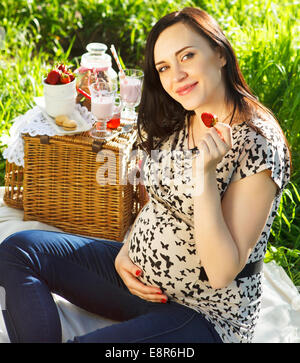 Ritratto di bella donna incinta a picnic nel parco di primavera Foto Stock