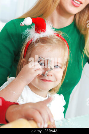 Due ragazze adorabili con la madre la cottura biscotti di Natale in cucina Foto Stock