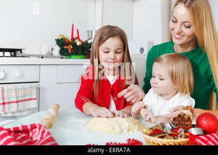 Due adorabili ragazze con sua madre la cottura biscotti di Natale in cucina Foto Stock