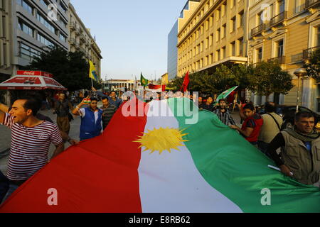 Atene, Grecia. 13 ottobre 2014. Protester portano una grande bandiera curda attraverso le strade di Atene. Curdi che vivono in Grecia hanno protestato contro gli attacchi di uno Stato islamico (SI) sulla città di Kobane in Siria. La loro rabbia è stata prevalentemente orientata verso la Turchia e la inattività dell'esercito turco di venire in aiuto della città assediata. Foto Stock