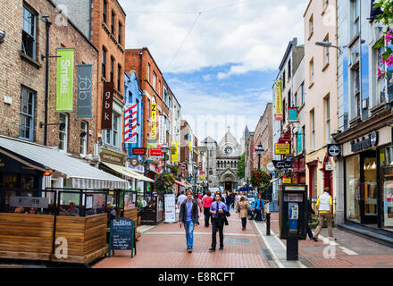 Negozi, bar e ristoranti su Anne Street South con St Ann's chiesa in distanza, Grafton Street area, Dublino, Irlanda Foto Stock