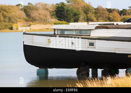 Houseboat fissa permanentemente sollevato al di fuori dell'acqua sui blocchi in calcestruzzo. Foto Stock