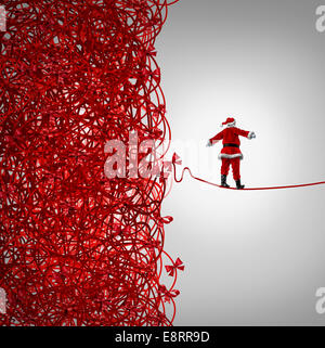 Santa Claus per la libertà e per la gestione delle feste regali di crisi come un concetto con santaclause come un funambolo camminando al di fuori di un confuso aggrovigliato caos dei nastri rossi rompere libera di un chiaro come una metafora per la gestione e per sfuggire allo stress di Natale. Foto Stock