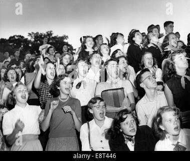 Anni Cinquanta gruppo ragazzi ragazze adolescenti folla in piedi il tifo guardando la High School del gioco del calcio Foto Stock