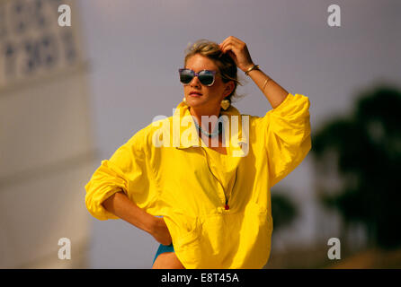 Degli anni Ottanta la donna a indossare occhiali da sole giallo demolitore DEL VENTO GIACCA A BEACH Foto Stock