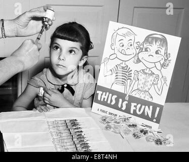 Anni Cinquanta bambina cercando fino circa a ottenere la vaccinazione antipolio a scuola firmare questo è divertente con connettori lollipop Foto Stock