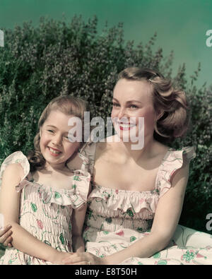 Negli anni quaranta anni cinquanta ritratto sorridente MADRE E FIGLIA DI ADATTAMENTO che indossa abiti di Sun all'aperto Foto Stock