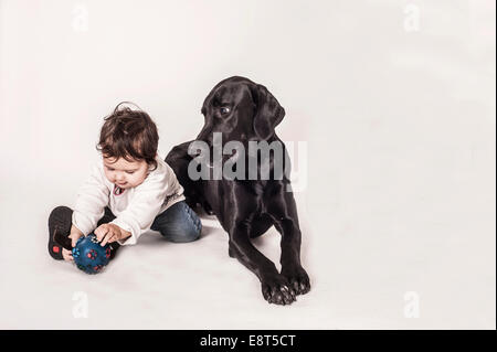 Grande nero mongrel che giace accanto a un bambino piccolo Foto Stock