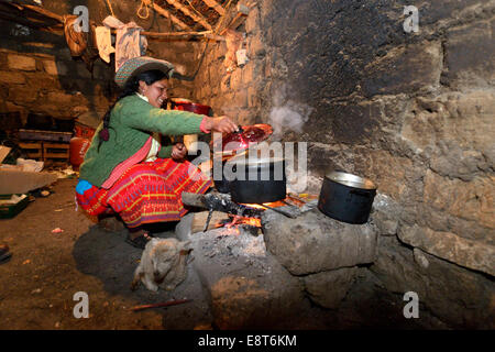 Giovane donna per la cottura sul fuoco aperto nella sua cucina tradizionale, Unione Potrero, Quispillacta, Ayacucho, Perù Foto Stock