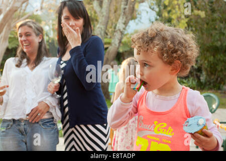 Ragazza giovane di mangiare la sua torta di coppa a una festa. Foto Stock