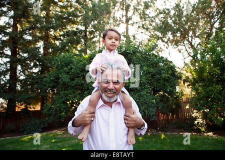 Nonno nipote che porta sulle spalle in cortile Foto Stock