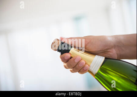 Close up di razza mista uomo apertura della bottiglia di champagne Foto Stock