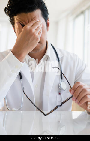 Close up di sconvolgere miscelati medico di gara lo sfregamento sulla sua fronte Foto Stock