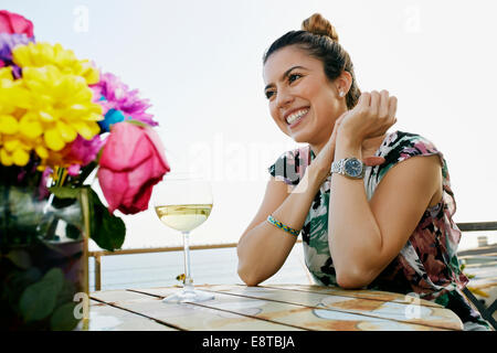 Razza mista donna bere vino a waterfront Foto Stock