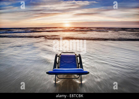 Sedia a sdraio affacciato sul tramonto sulla spiaggia Foto Stock