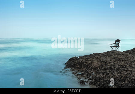 Sedia onde che si affaccia sulla spiaggia rocciosa Foto Stock