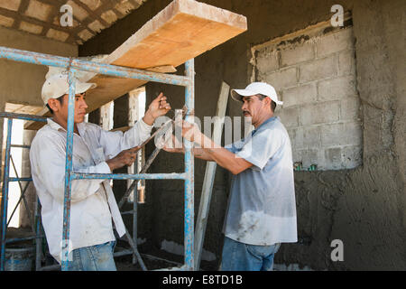 Ispanico lavoratori edili con i ponteggi al sito in costruzione Foto Stock