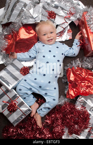 Bambino sulla commedia colpo di sfondo in un studio di indossare abbigliamento fresco al tempo di Natale, con presenta e carta da imballaggio, Foto Stock