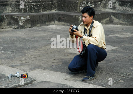 Un maschio asiatici tourist è pronta per scattare una foto con un sacco di altre telecamere ai suoi piedi Foto Stock