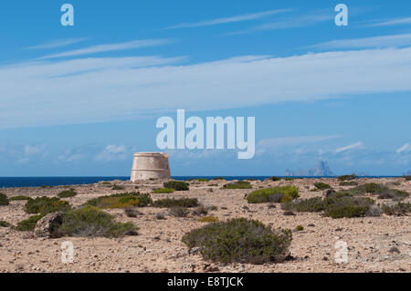 Fomentera, isole Baleari: vista di theMediterranean macchia e la Gavina Tower, una torre di avvistamento costruita nel 1763 per il controllo della costa ovest dell'isola Foto Stock