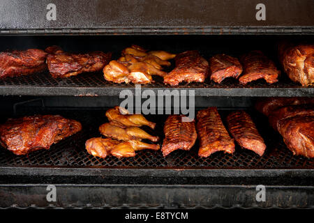 Pollo, punta di petto di manzo e costolette di maiale nel fumatore. Foto Stock