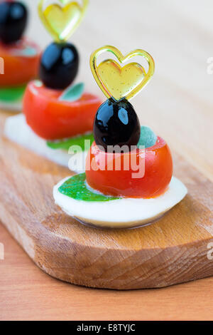 Semplice spuntino crostino con pomodoro, mozzarella e basilico close-up su sfondo di legno Foto Stock