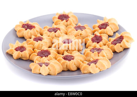 Biscotti dolci con marmellata su lastra grigia isolati su sfondo bianco. Foto Stock